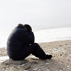 Image showing Lonely man sitting on sand