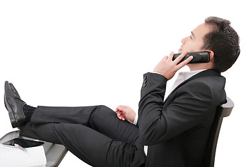 Image showing young business man relaxing at office desk and talking on mobile