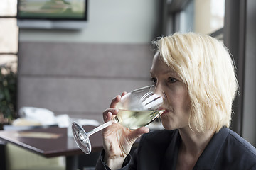 Image showing Blonde Woman with Beautiful Blue Eyes Drinking Glass of White Wi