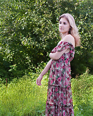 Image showing Beautiful girl in floral dress stand in garden.