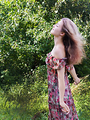 Image showing Beautiful girl in floral dress stand in garden.