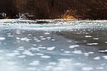 Image showing Frozen river with blue ice and sun reflection. Selective focus.