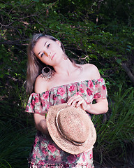 Image showing Beautiful girl in the national dress and hat stand in the forest