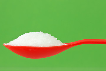 Image showing spoon with sugar on green background