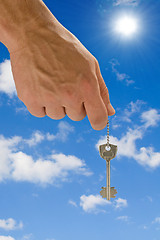 Image showing hand holding key on sky background