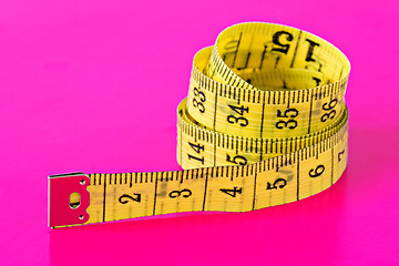 Image showing measuring tape on vivid pink background