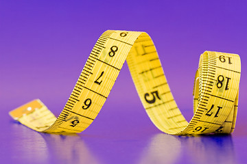 Image showing yellow measure tape on purple