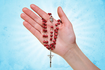 Image showing hand with rosary on blue abstract background