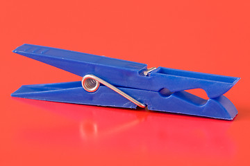 Image showing blue plastic clothespin on red background