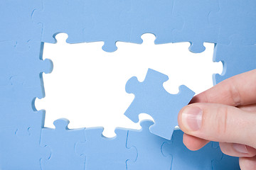 Image showing Hand collecting  blue puzzle 