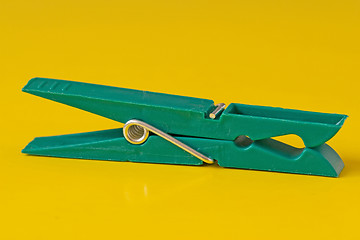 Image showing green plastic clothespin on yellow background