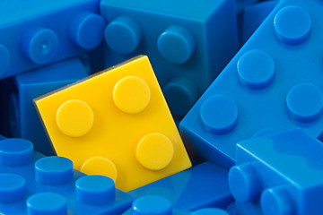 Image showing yellow plastic brick in a middle of blue ones