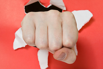 Image showing Hand punching through red paper 