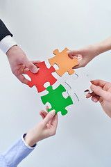 Image showing Group of business people assembling jigsaw puzzle