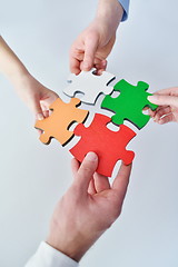 Image showing Group of business people assembling jigsaw puzzle