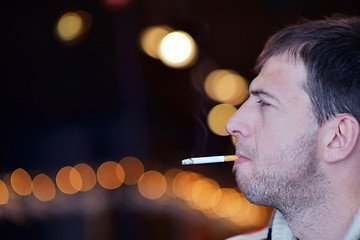 Image showing man smokes a cigaret against a dark background