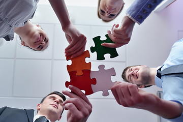 Image showing Group of business people assembling jigsaw puzzle