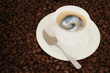 Image showing cup of coffee with teaspoon on coffee beans background 
