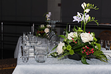 Image showing Flower composition of freesia, roses and hypericum on tables set