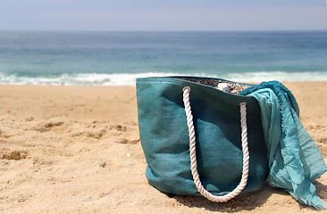 Image showing Blue beach bag on the seacoast and shawl  