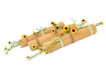 Image showing Uncooked Italian spaghetti decorated with yellow flowers isolate