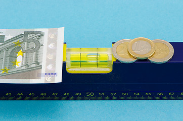 Image showing construction level tool euro banknote coin on blue 