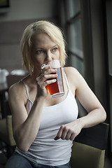 Image showing Blonde Woman with Beautiful Blue Eyes Drinking Glass of Pale Ale