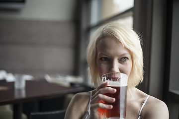 Image showing Blonde Woman with Beautiful Blue Eyes Drinking Glass of Pale Ale