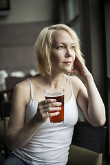 Image showing Blonde Woman with Beautiful Blue Eyes Drinking Glass of Pale Ale