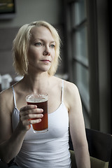 Image showing Blonde Woman with Beautiful Blue Eyes Drinking Glass of Pale Ale