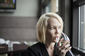 Image showing Blonde Woman with Beautiful Blue Eyes Drinking Glass of White Wi