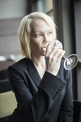 Image showing Blonde Woman with Beautiful Blue Eyes Drinking Glass of White Wi