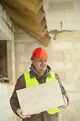 Image showing Builder with concrete block near new building