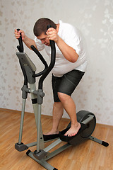Image showing overweight man exercising on trainer