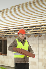 Image showing Builder with roof tiles near new building