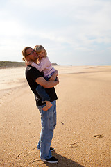 Image showing Father holding daughter in arms at the beach