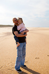 Image showing Father holding daughter in arms at the beach