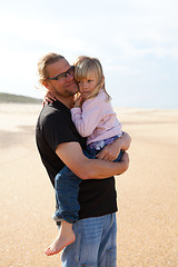 Image showing Father holding daughter in arms at the beach