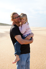 Image showing Father holding daughter in arms at the beach