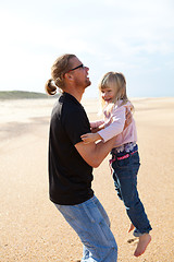 Image showing Father holding daughter in arms at the beach