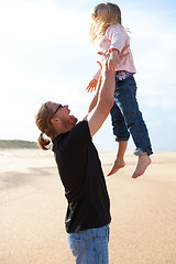 Image showing Father throwing daughter in the air at the beach