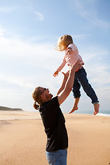 Image showing Father throwing daughter in the air at the beach