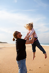 Image showing Father throwing daughter in the air at the beach