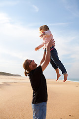 Image showing Father throwing daughter in the air at the beach