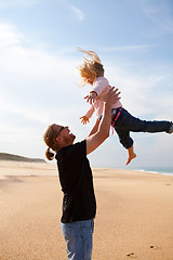 Image showing Father throwing daughter in the air at the beach