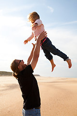 Image showing Father throwing daughter in the air at the beach