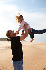 Image showing Father throwing daughter in the air at the beach