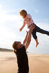 Image showing Father throwing daughter in the air at the beach