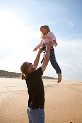 Image showing Father throwing daughter in the air at the beach