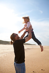 Image showing Father throwing daughter in the air at the beach